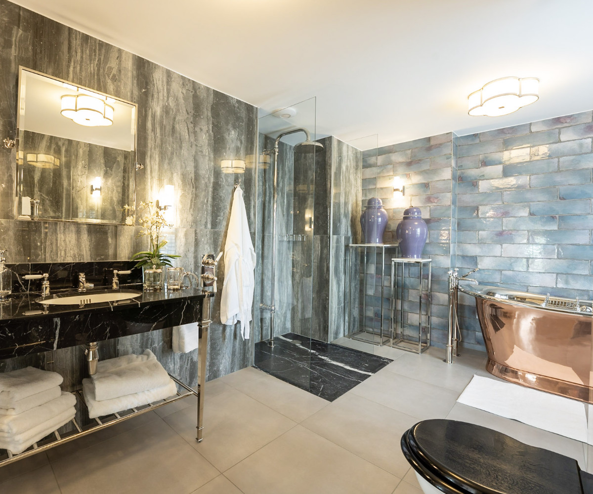 A dramatic luxury bathroom with dark slate tiles and copper fixtures - interior design by Atlantic Interiors