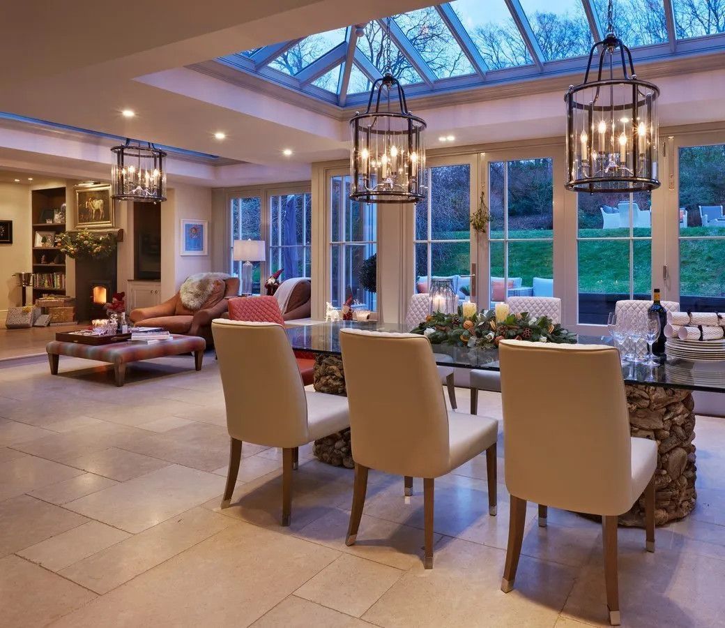 The open-plan kitchen orangery dining room with statement pendant lantern lights, dining table and chairs, and a glazed roof - interior design by Atlantic Interiors, Kent

