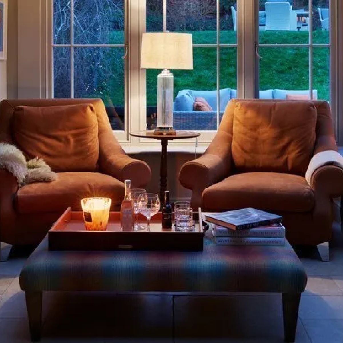 A cosy snug seating area within the Kitchen Orangery - leather sofa, warm lamp and atmospheric evening lighting, Kent
