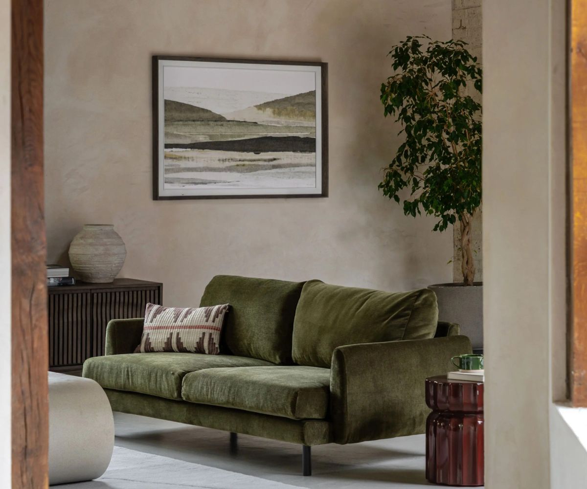A luxury olive green sofa in a beautifully designed interior with a landscape artwork - Atlantic Interiors furniture and procurement