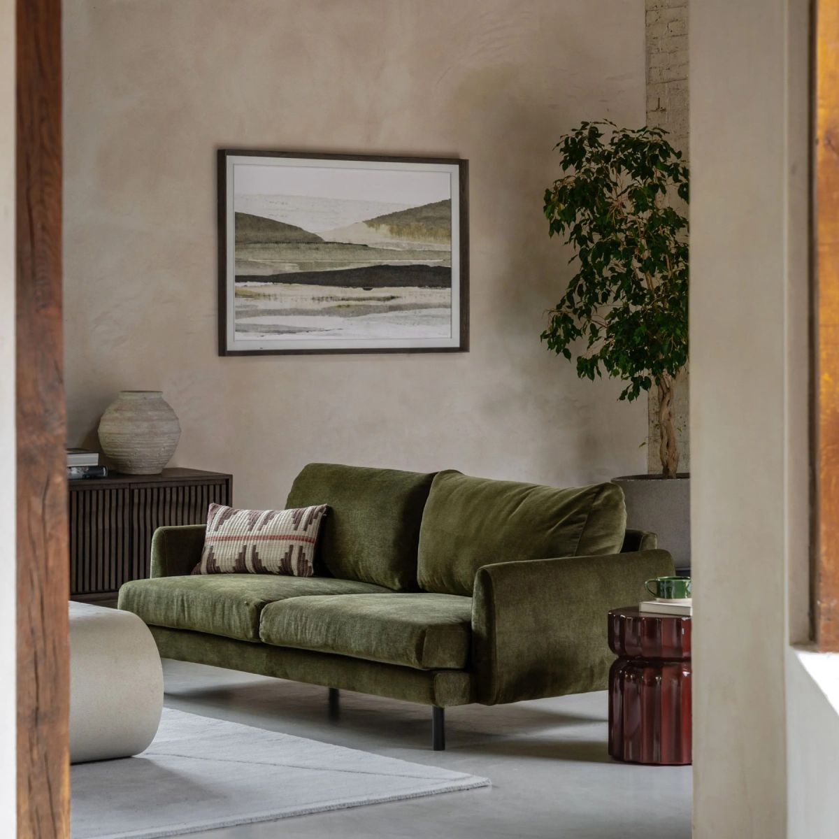 A luxury olive green sofa in a beautifully designed interior with a landscape artwork - Atlantic Interiors furniture and procurement
