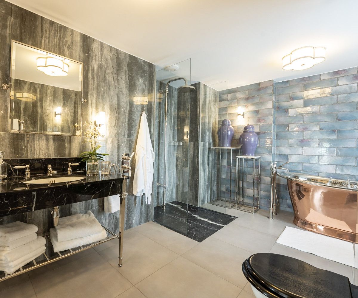 A dramatic luxury bathroom with dark slate tiles and copper fixtures - interior design by Atlantic Interiors