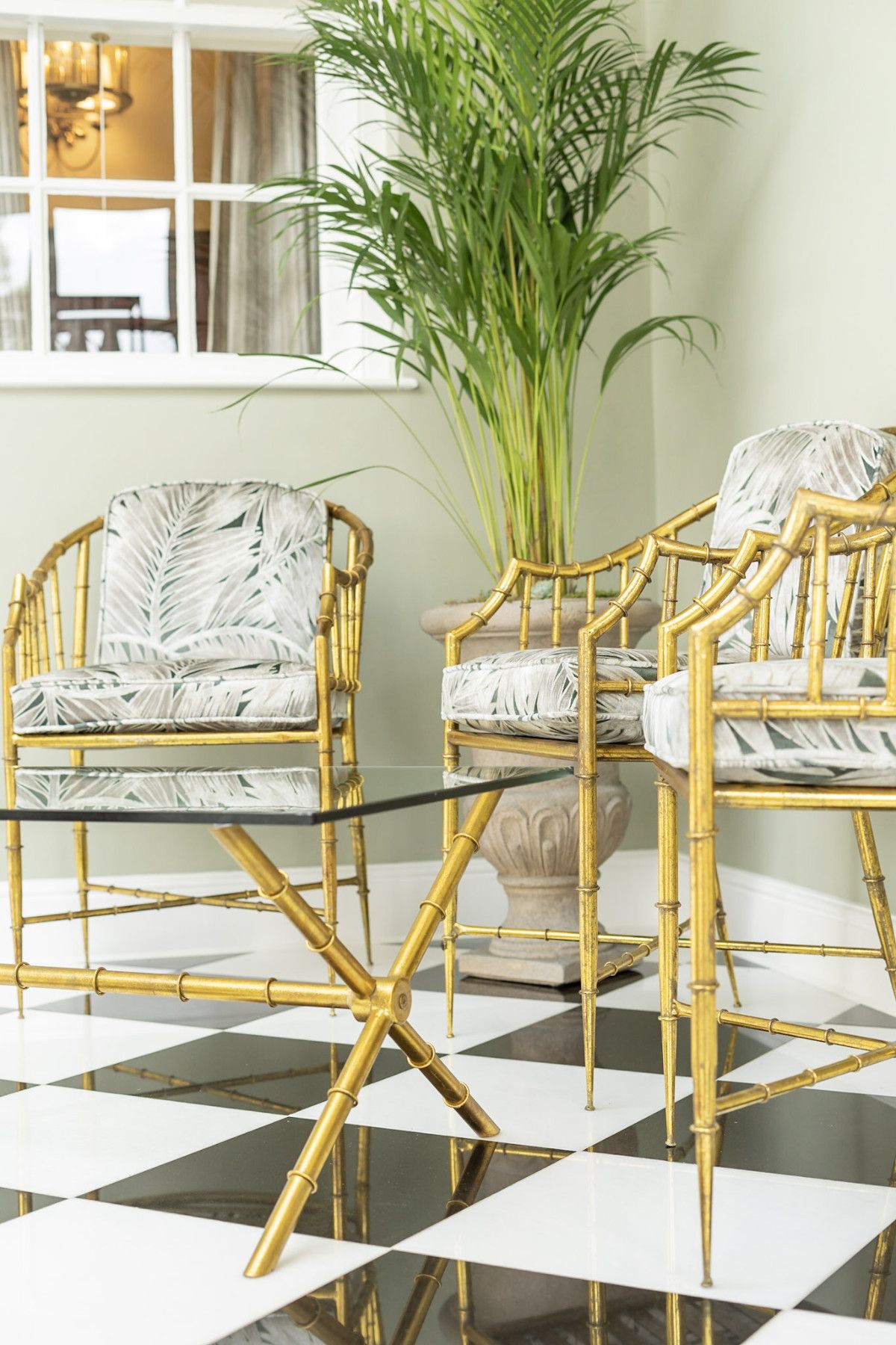 Gold faux-bamboo chairs with palm leaf print cushions on a black and white checkered floor — interior design by Atlantic Interiors, Coastal Residence Kent